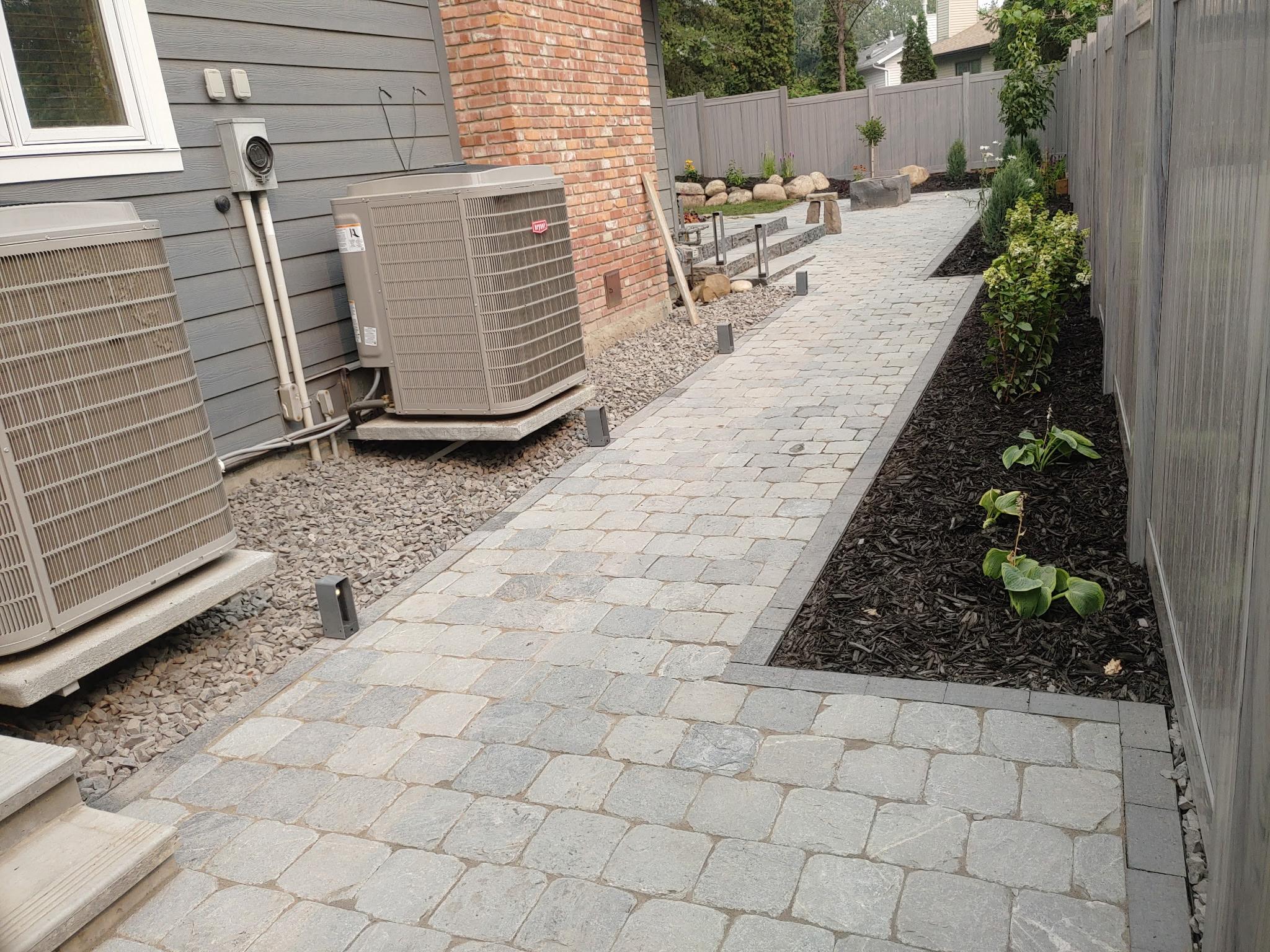 Side yard paver walkway with gravel border along vinyl fence